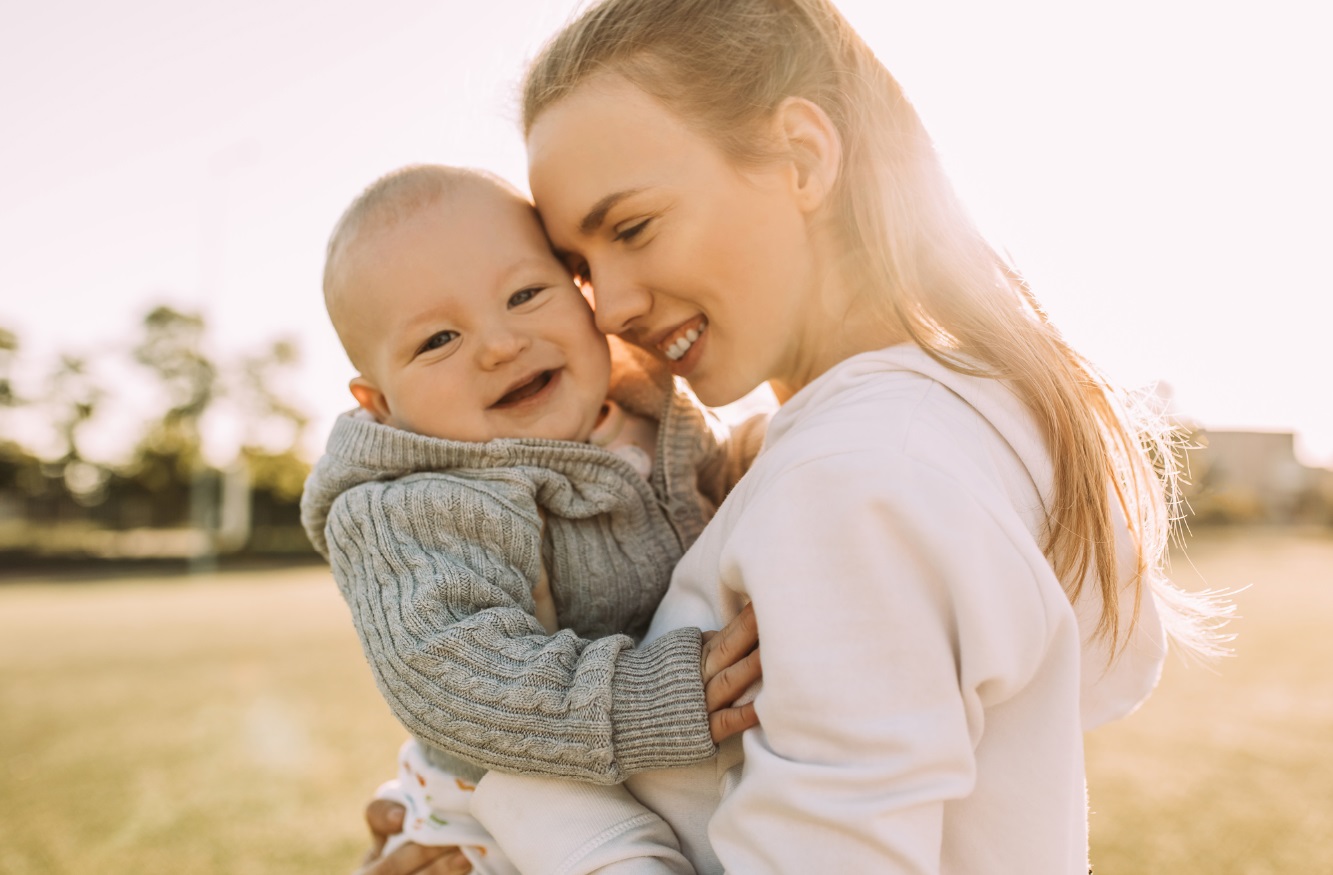 glückliche Mama mit lachendem Baby auf dem Arm